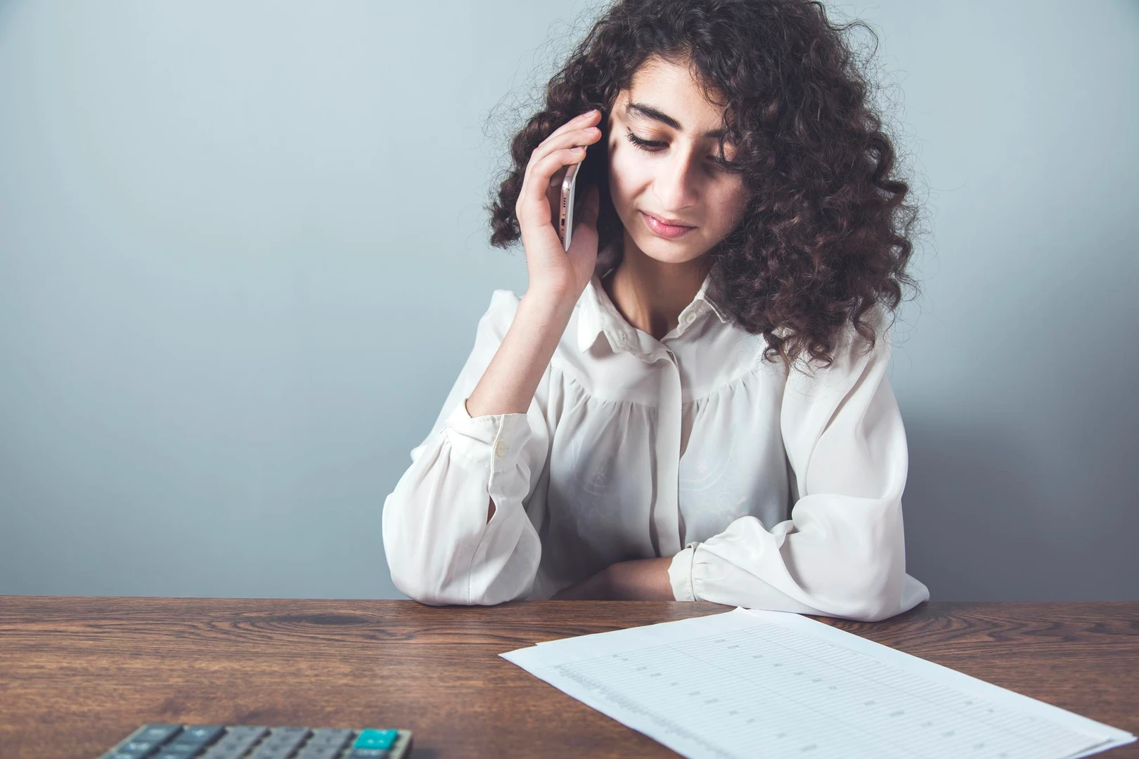 Mujer revisa en su celular la diferencia entre interés y mora en un préstamo junto a sus documentos